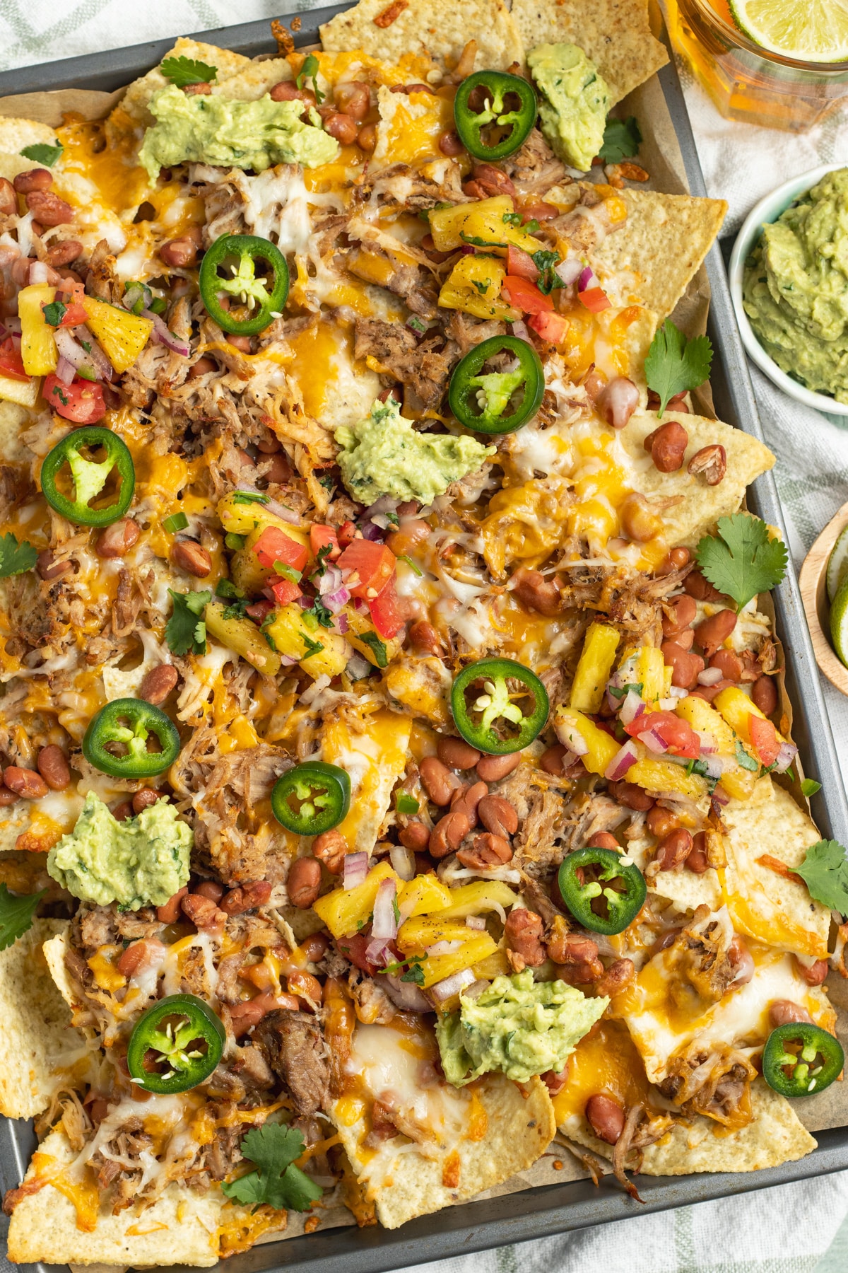 This is a picture of a large plate of loaded carnitas nachos.
