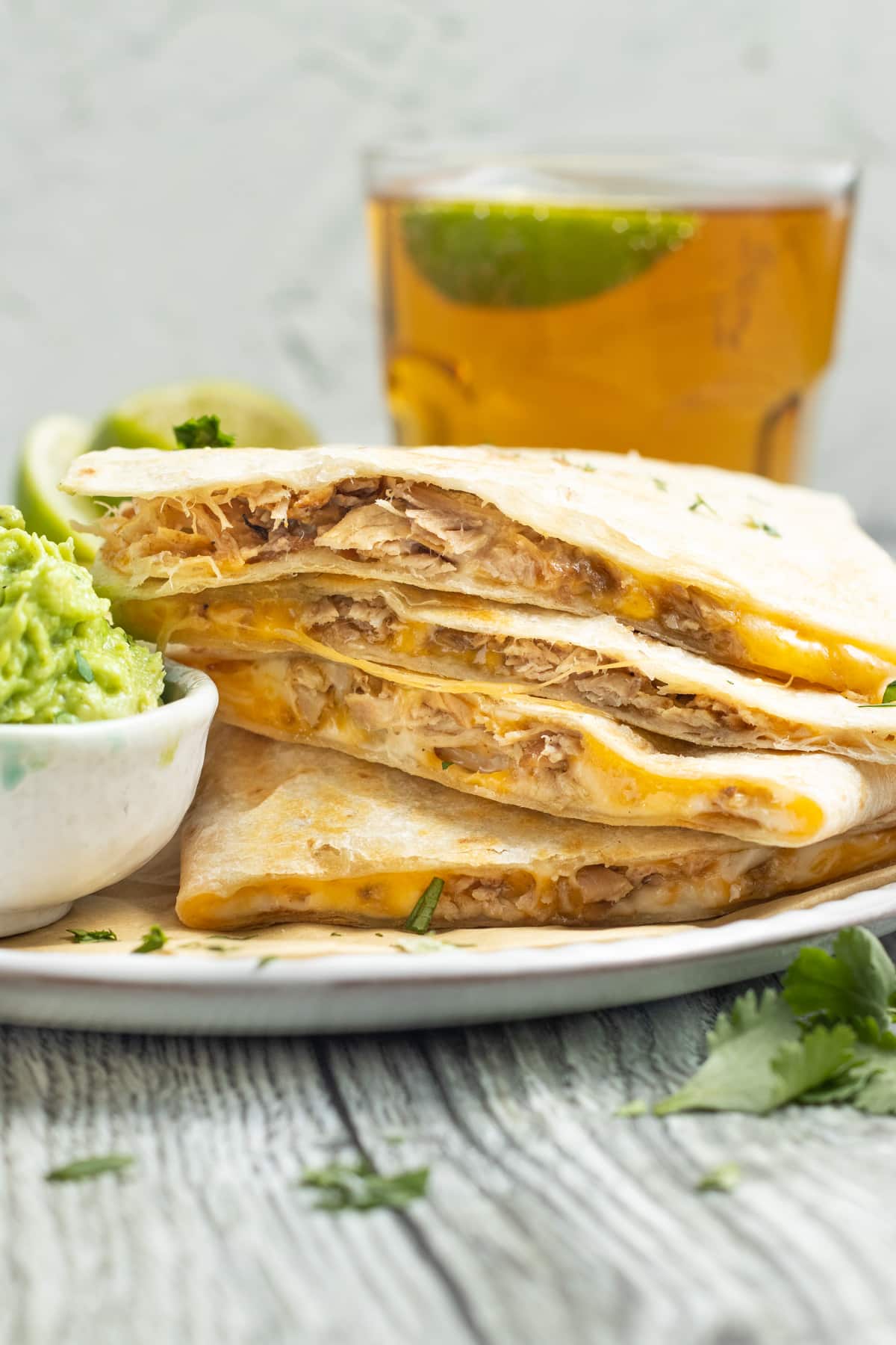 This is a picture of a carnitas quesadilla with a glass of beer in the background.