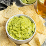 This is a picture of a bowl of guacamole with chips