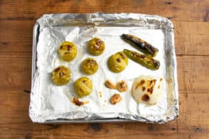 This is a picture of all the ingredients of this tomatillo salsa on a baking sheet after roasting.