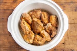 This is a picture of the pork added to the crockpot with seasoning.