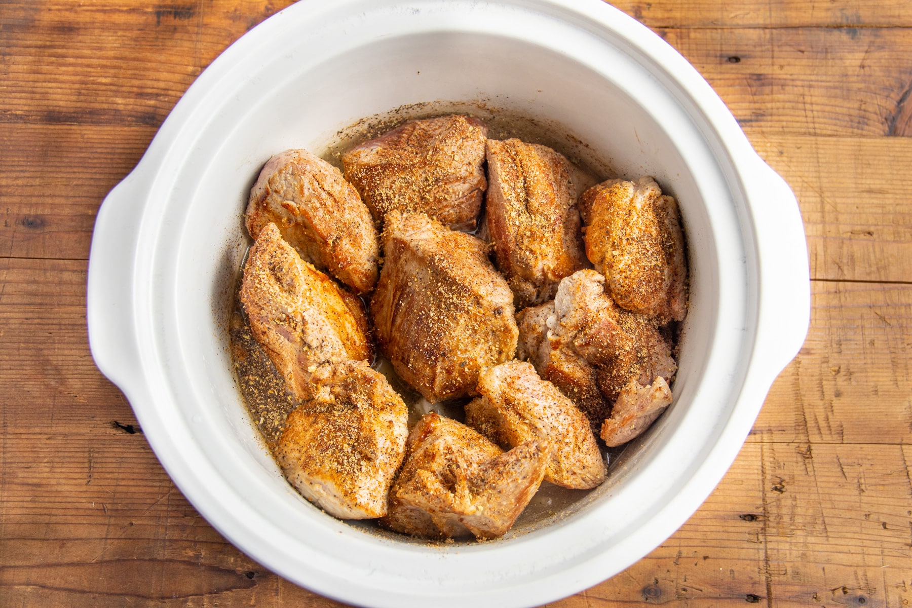 This is a picture of the pork added to the crockpot with seasoning.