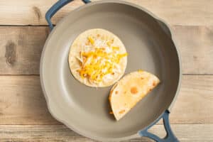 This is a picture of a skillet with the taco cooking with cheese.