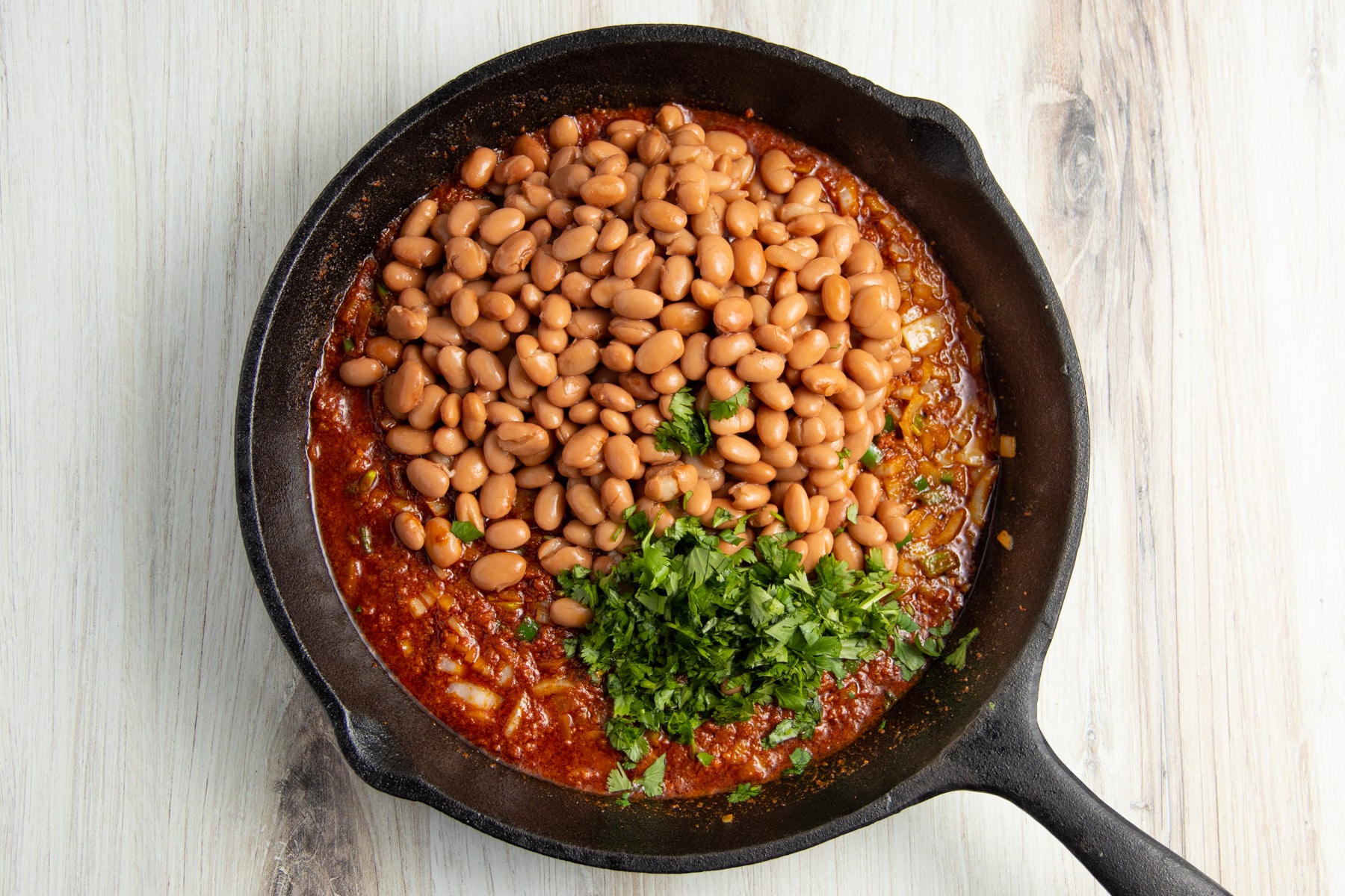 This is a picture of the chorizo onion and jalapeño in a skillet with beans added.