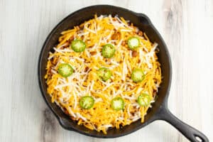 This is a picture of the chorizo onion and jalapeño in a skillet with beans and cheese on top.